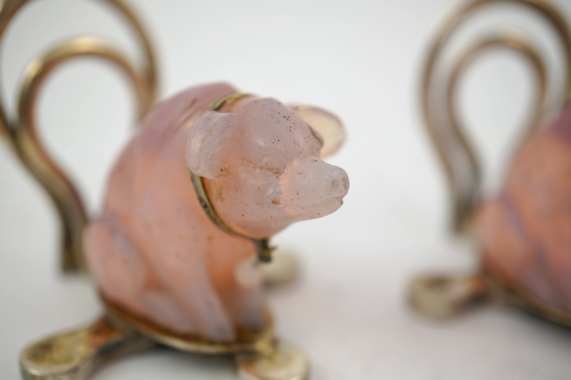 A cased pair of unusual Edwardian silver and pink glass mounted menu holders, by William Comyns, each modelled as a seated pig with collar